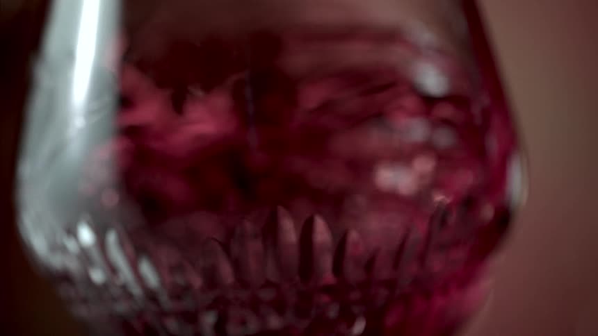Close up of a red drink stirred in wine glass in a circular motion