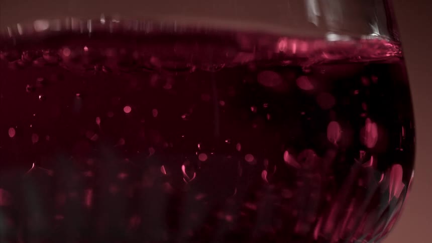 Close up of a red drink bubbling as it is poured into a glass cup