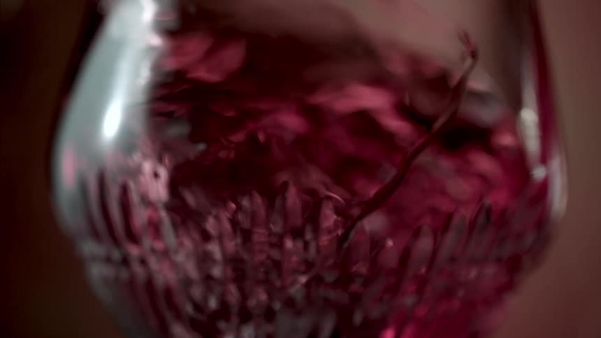 Close up of a red drink in a glass cup stirred in the air