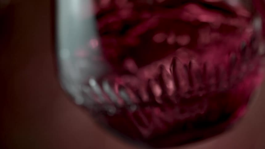 The wine mixes and is being shook in the glass