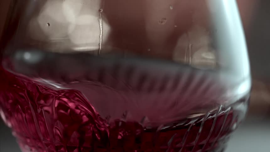 Close up of a red drink stirred in a glass cup on a table surface