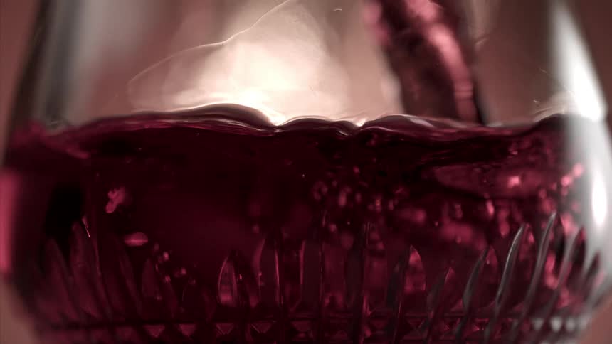 Close up of a glass cup with a red drink being poured into it