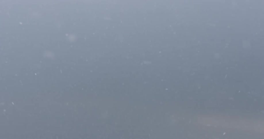 Snow moves around this cloudy skyline