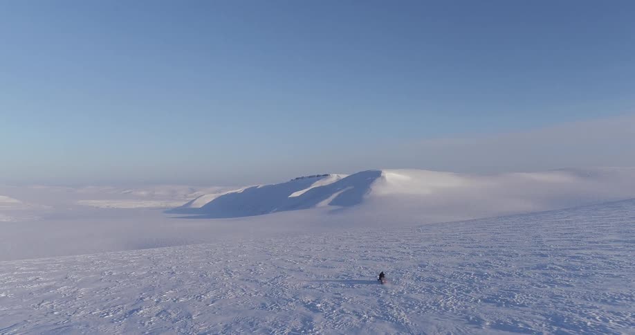 A snowmobile races towards the snow mountains