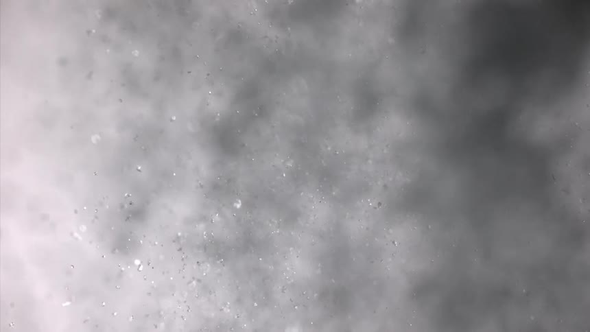 Water splashes into the air breaking apart into shimmering droplets as it scatters in all directions