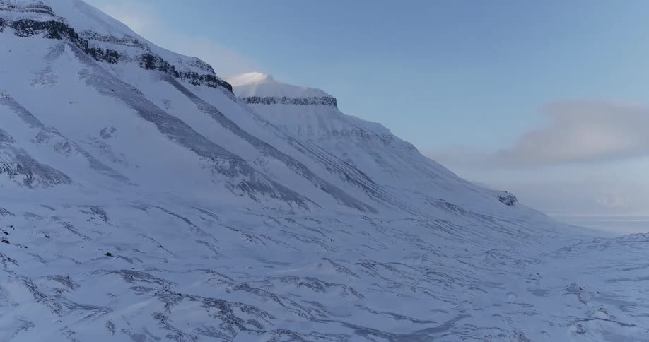 The mountain is covered with snow and is steep