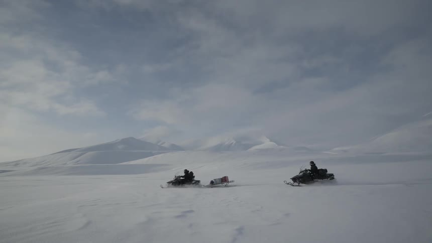 Two snowmobiles are racing on a field