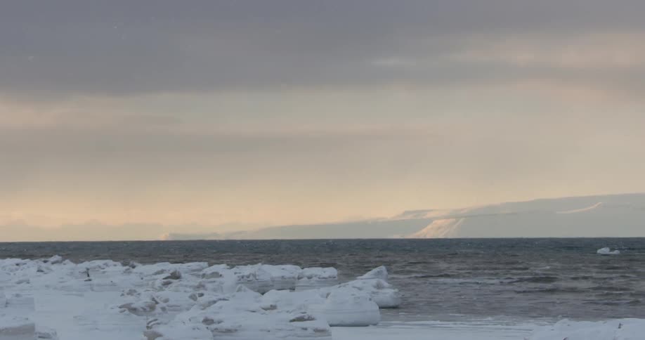 Snow falls on a body of water