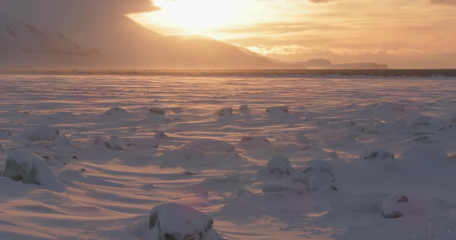 A view of large snow covered rocks with the sun setting