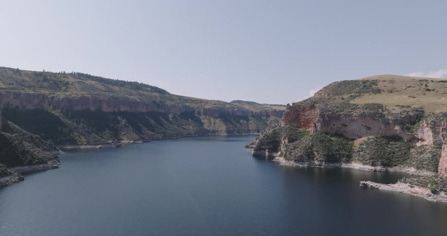 A wide scenic aerial view of a calm river flowing through rocky hills and canyons