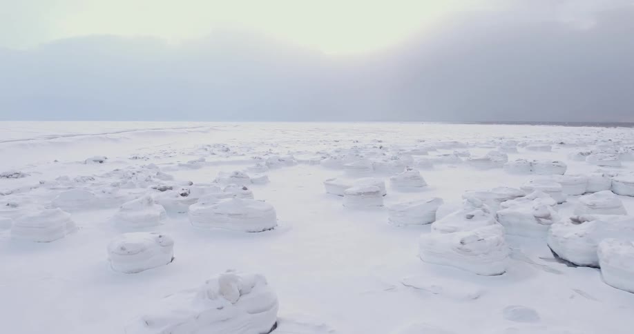 A view of a field like area covered with snow and large rocks