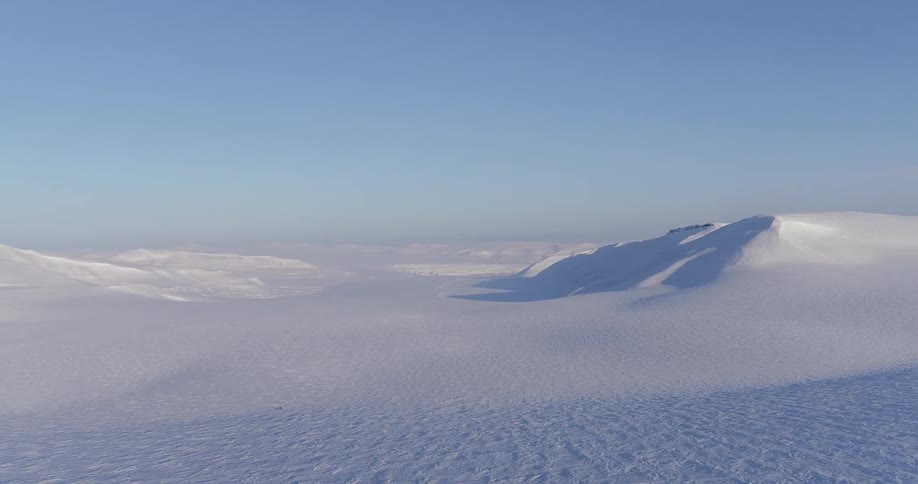 A long snow covered field has a clear sky above