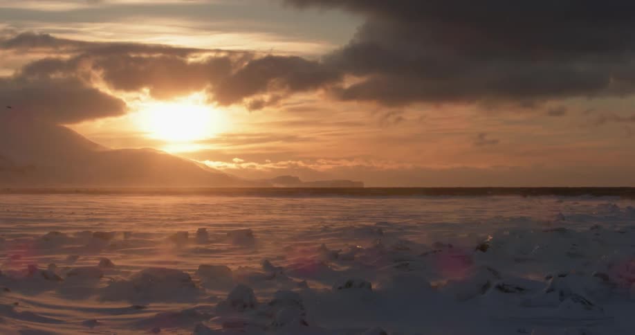The sun is setting over the ice covered field