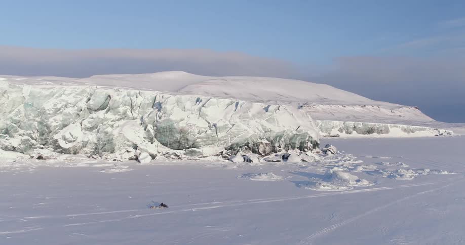 Person riding snowmobile through snow covered arctic wilderness