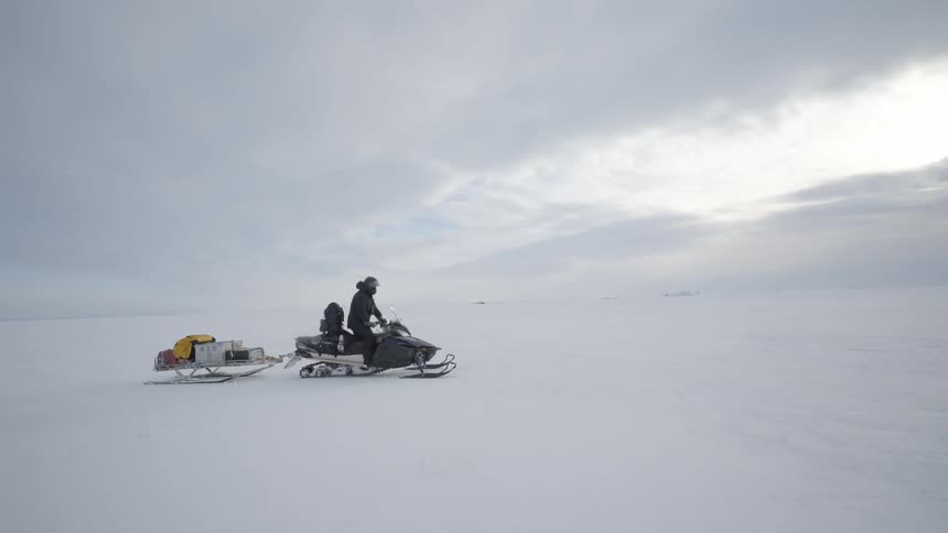 People riding snowmobiles in snow covered wilderness