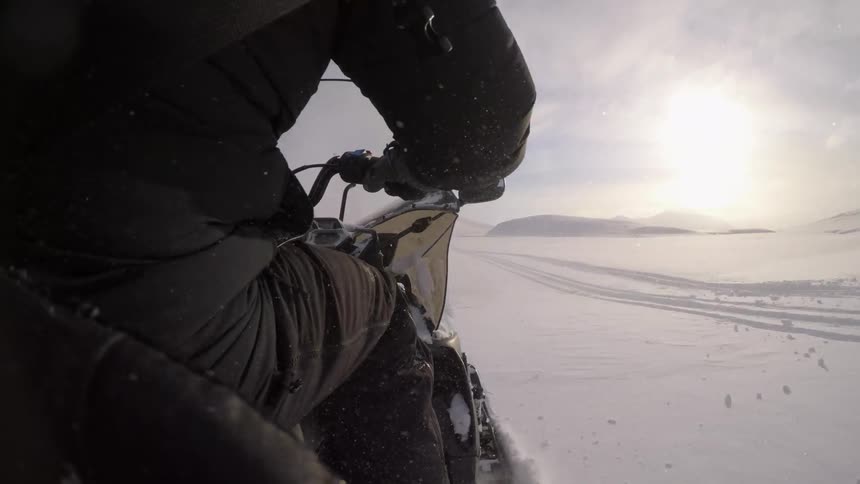 A person is racing in a snowmobile on a cloudy day