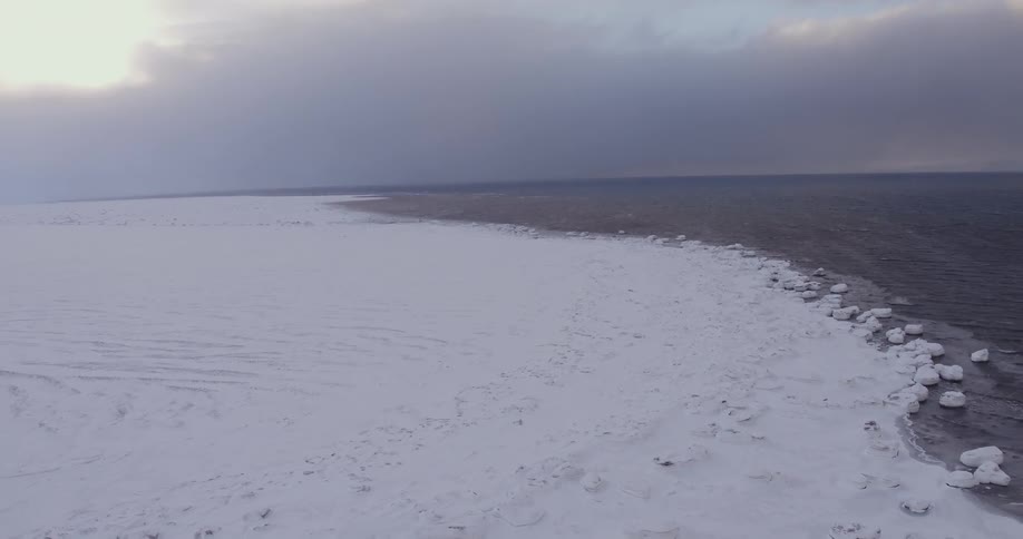 Snow covers the ground next to icy water