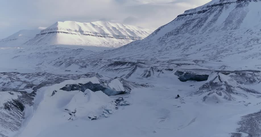 A person rides a snowmobile between snowy mountains