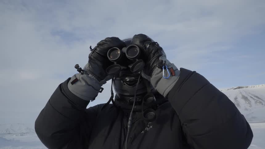 A man is using binoculars on a cloudy day