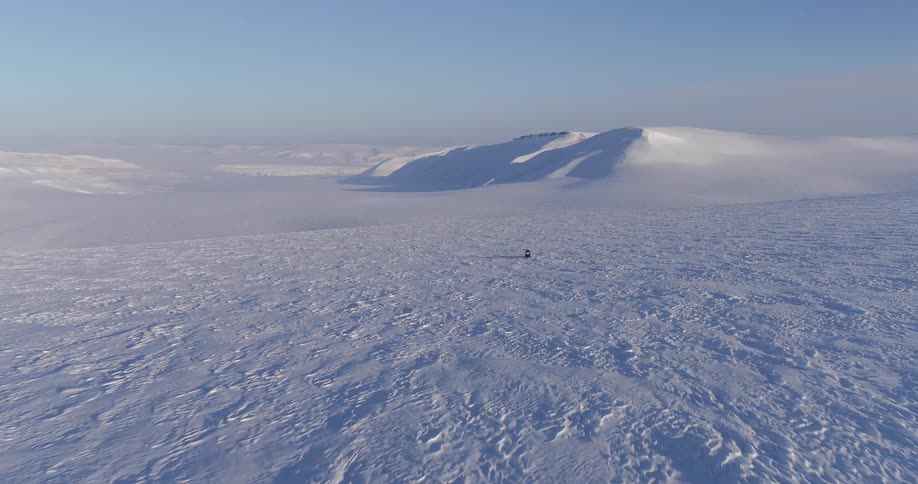 The field is covered with snow as a snowmobile races forward