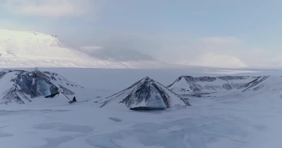 A snowmobile travels around some rocks on this icy field