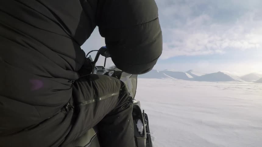 A person rides a snowmobile in the snowy wilderness
