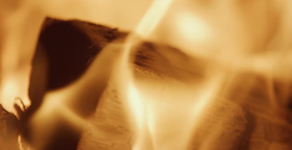 Flames flicker and rise from burning wood