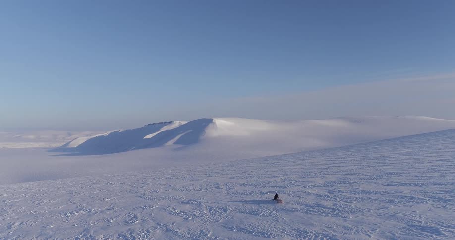 A snowmobile races towards the mountains ahead