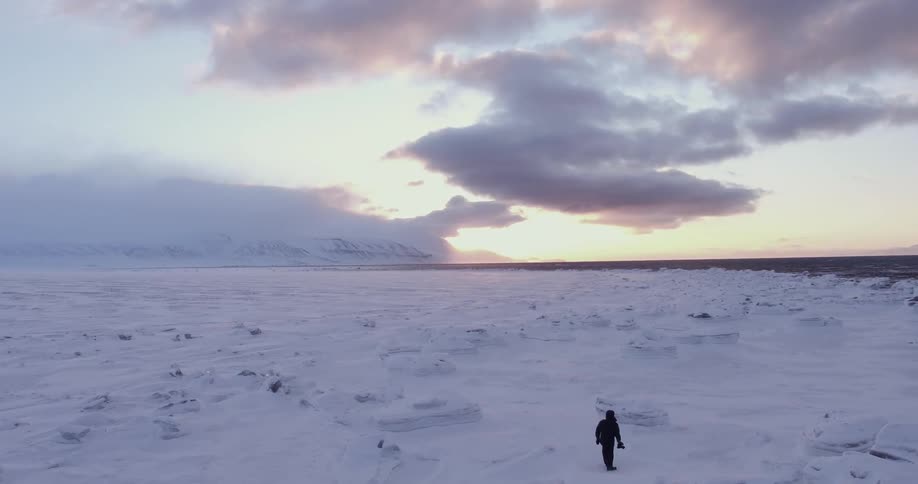 A person hikes over a snow covered field at dawn