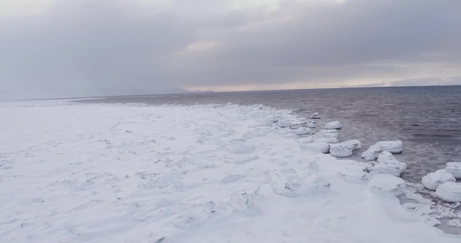 The icy shore has heavy clouds above