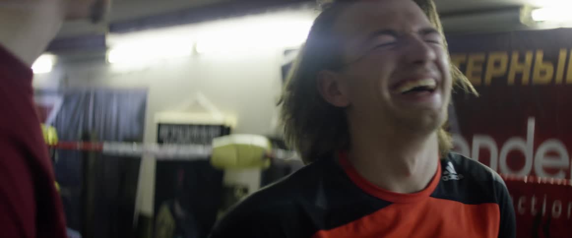A man is laughing talking with someone near a ring