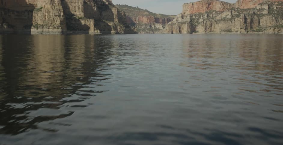 A calm river runs through a canyon with towering rocky cliffs on both sides