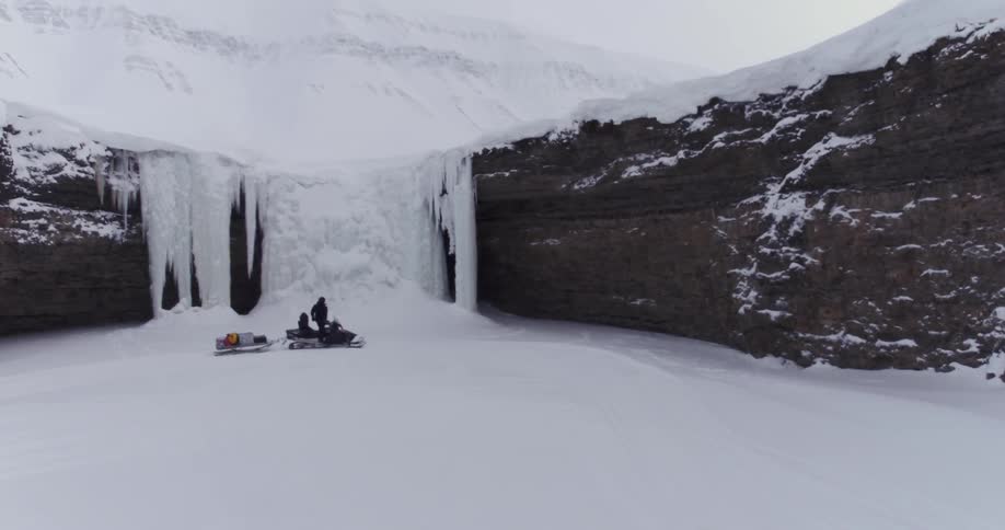 A snowmobile comes to a stop at a snow covered canyon wall