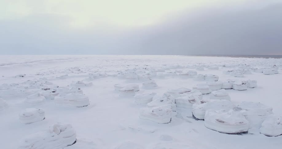 A field is covered with rocks ice and snow near the water