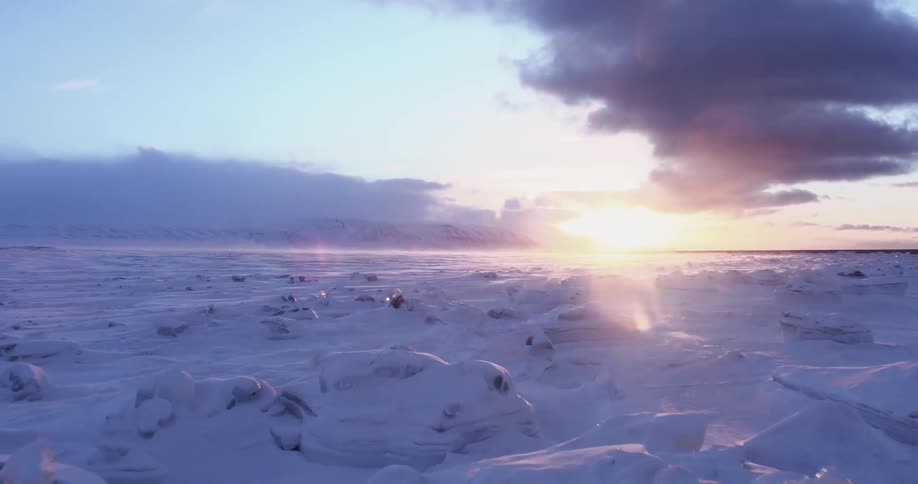 The field is covered with large rocks and snow at dawn