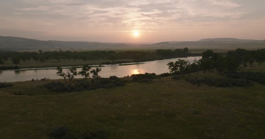 Landscape of the sun rising between mountains with a winding river in the foreground