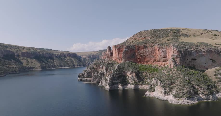 Cliffs lead down to slopes on the banks of a river on a cloudy summer day