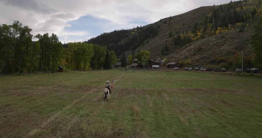 The woman is riding her horse to the gate of the ranch