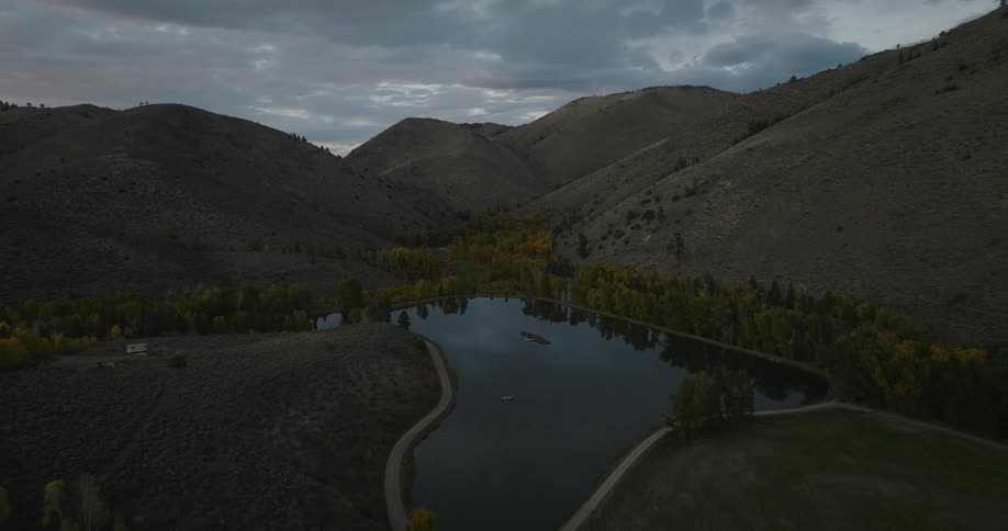 Aerial view of a calm mountain valley with a lake and autumn trees