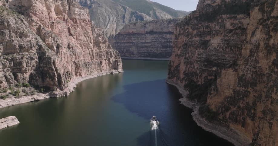 Boat sailing along the canyon walls of a mountain valley river