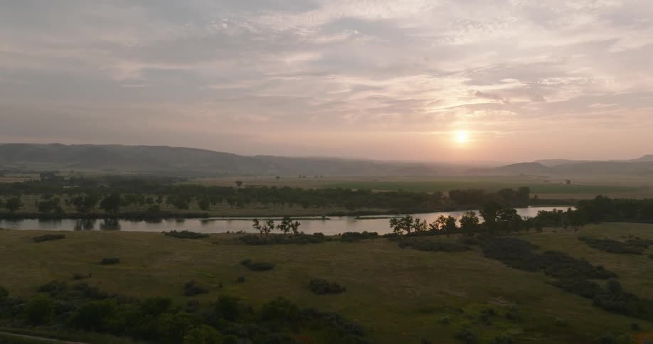 Aerial view of a grasscovered field with a small lake and a bridge