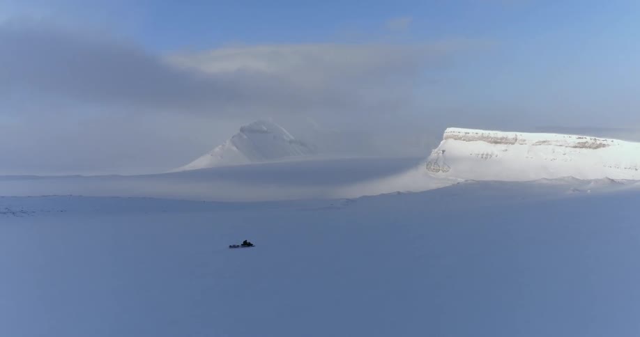 A snowmobile races along the field in the distance