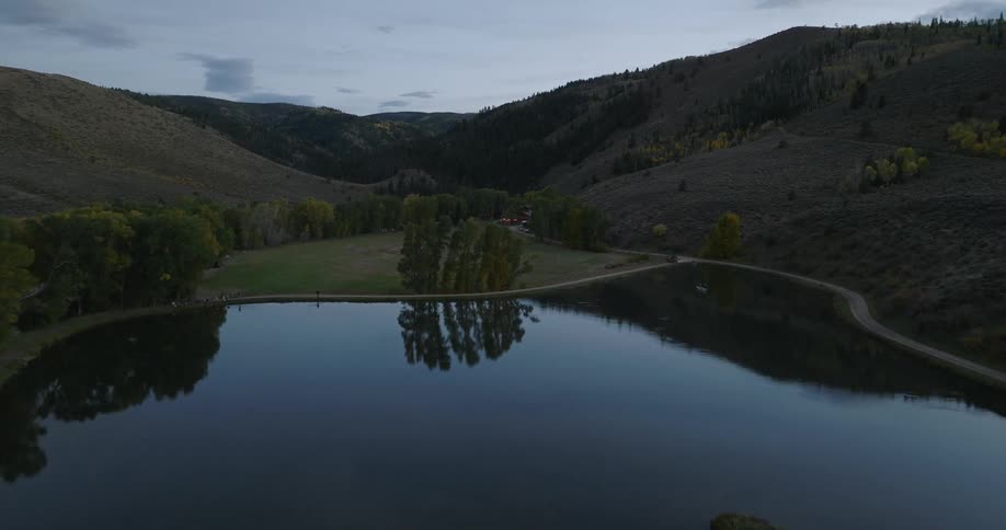 The sky reflects on the lake water by the hills
