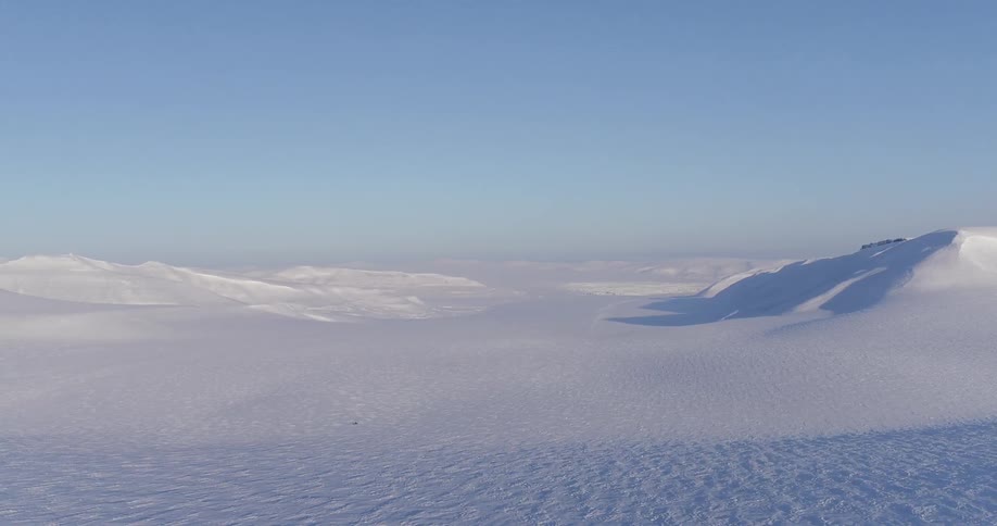 A long expansive field is covered with snow