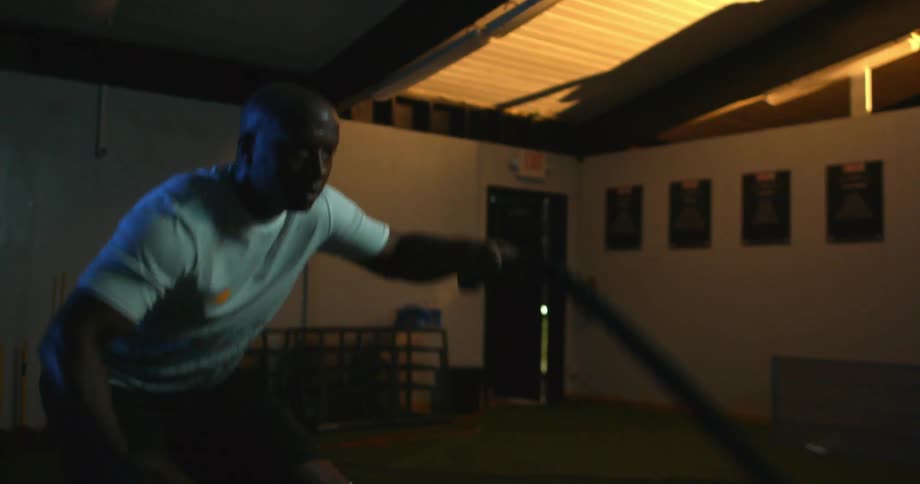 A man is in a gym pulling ropes