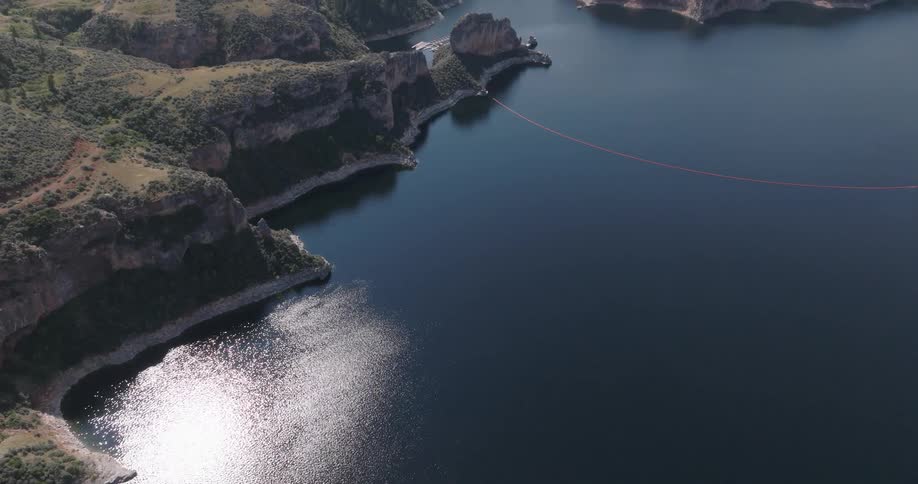 The ocean is calm at the shore near the extensive formation of cliffs