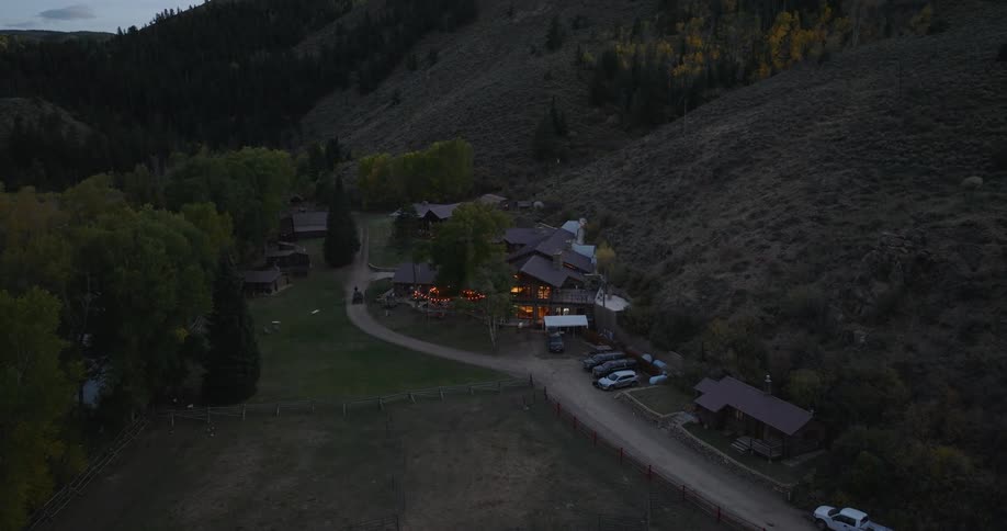A resort surrounded by forest and mountains with cars parked in the garage