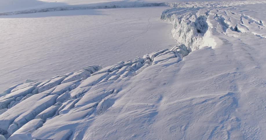 A large boulder covered in snow and an open field covered in snow