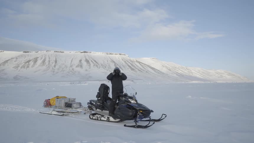 A man takes photographs from a snowmobile