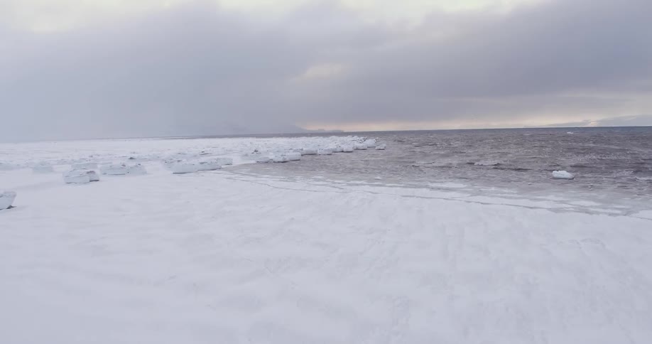 An open area covered in snow and the other part covered in water